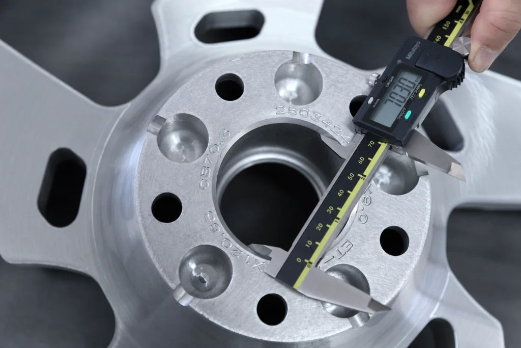 Digital caliper measuring the center bore during forged wheel inspection