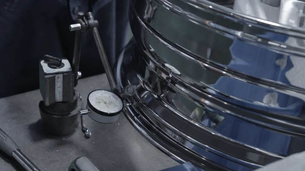 Dial indicator positioned against a wheel during a runout check