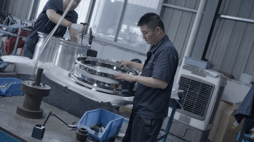 Technician examining a polished wheel component at a workbench