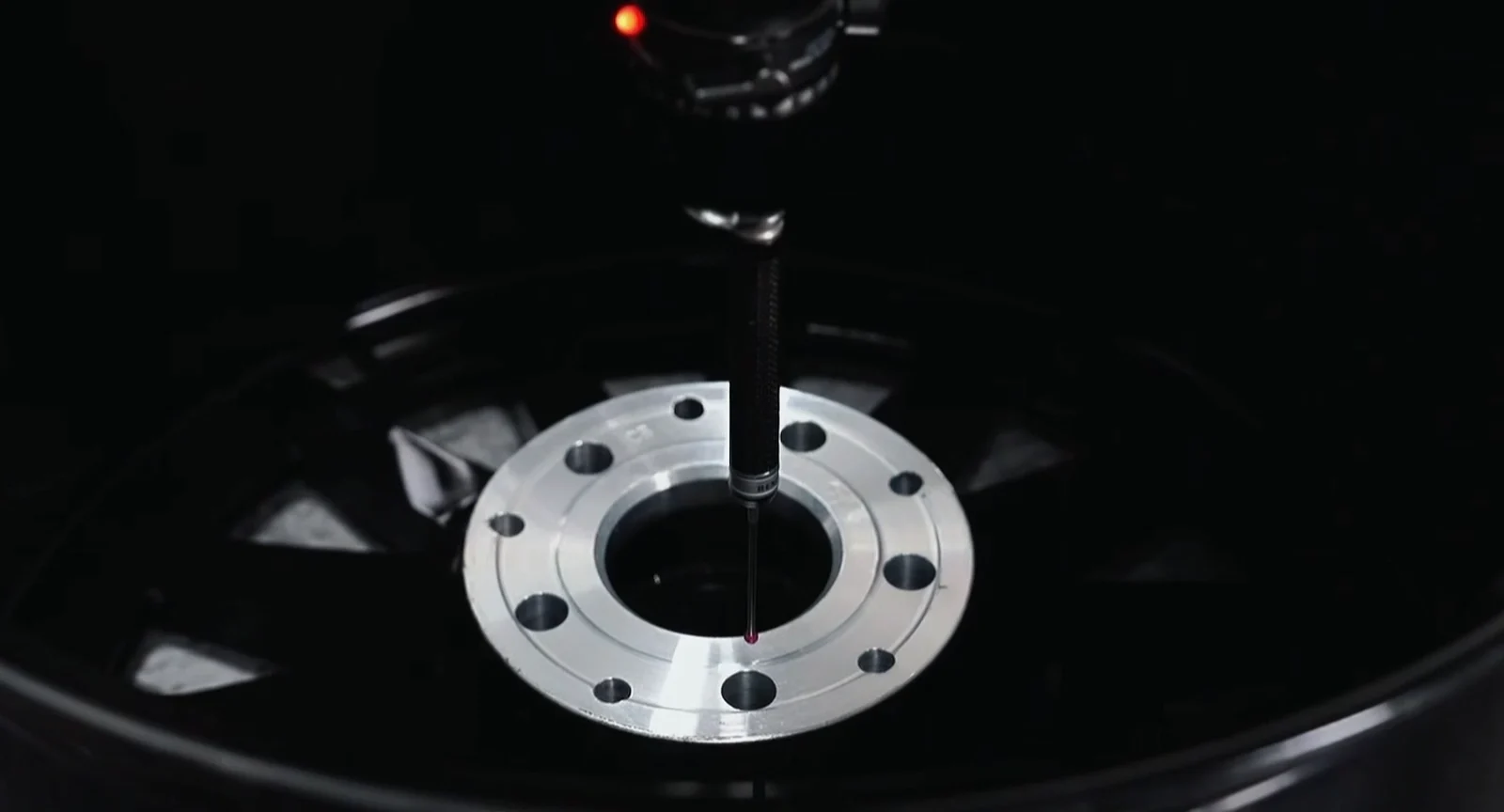 Measuring probe checking the center bore area of a forged wheel