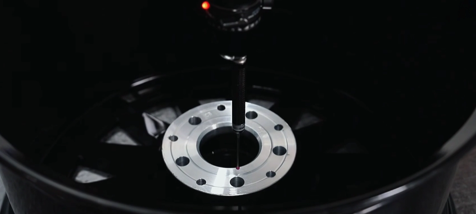 Measuring probe checking the center bore area of a forged wheel